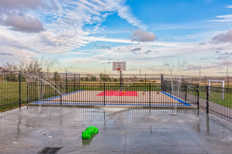 Basketball court with a sprinkler on a wet ground in the foreground