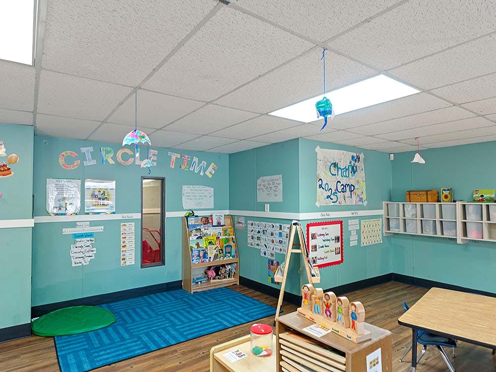 Classroom with light blue walls and a rug, reading nook, and whiteboard