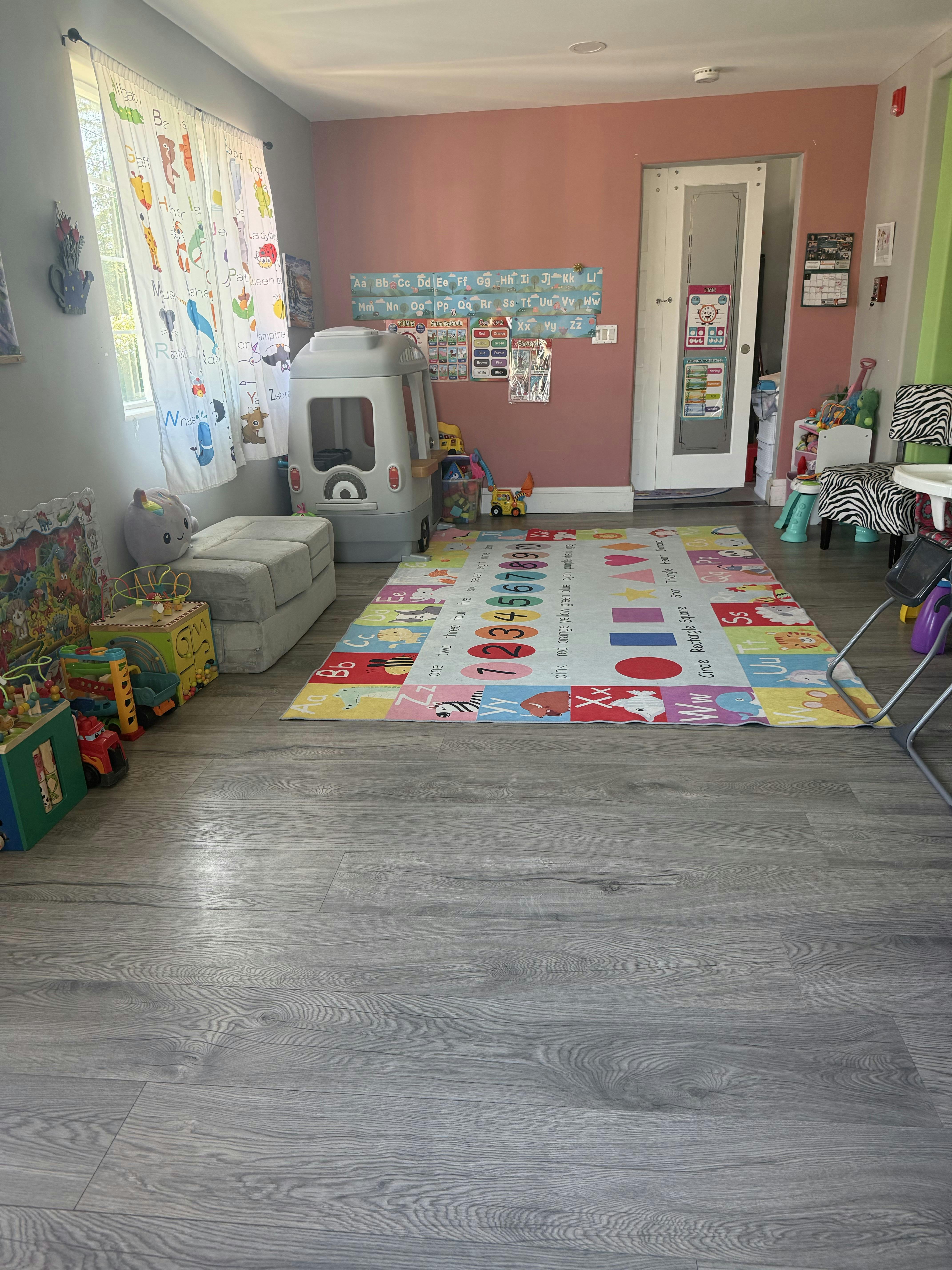 Children's playroom with ABC rug, toys, and alphabet curtains
