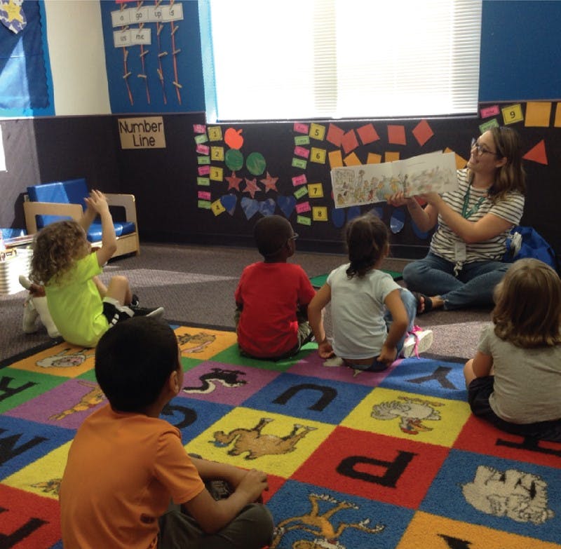 Adult reading a book to children in a classroom