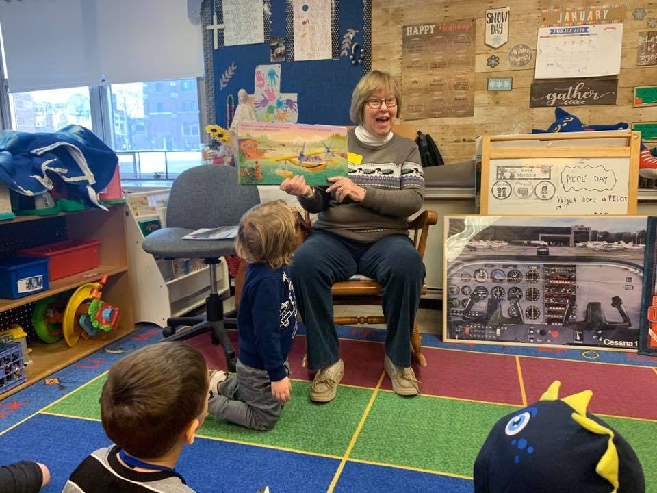 Person reading a book to children in a classroom