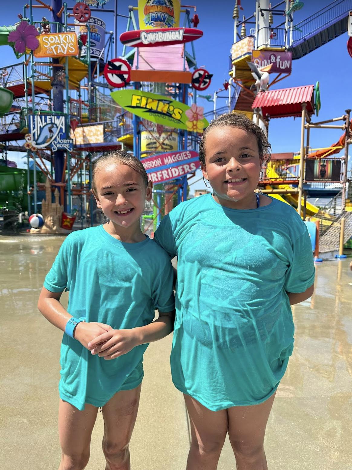 Two children standing in front of a water park structure