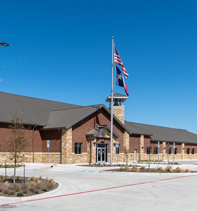 Building with brick and stone facade, flagpole with two flags