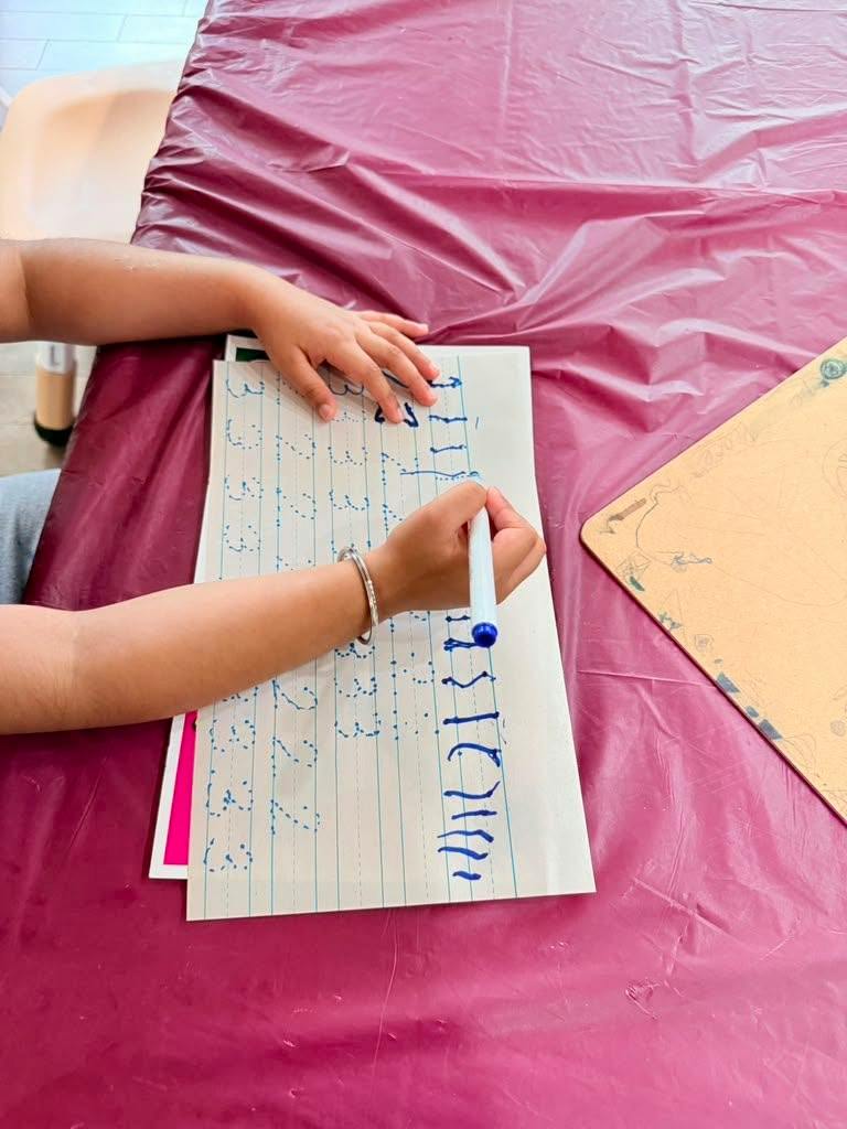 Child practicing writing numbers on a worksheet with a marker