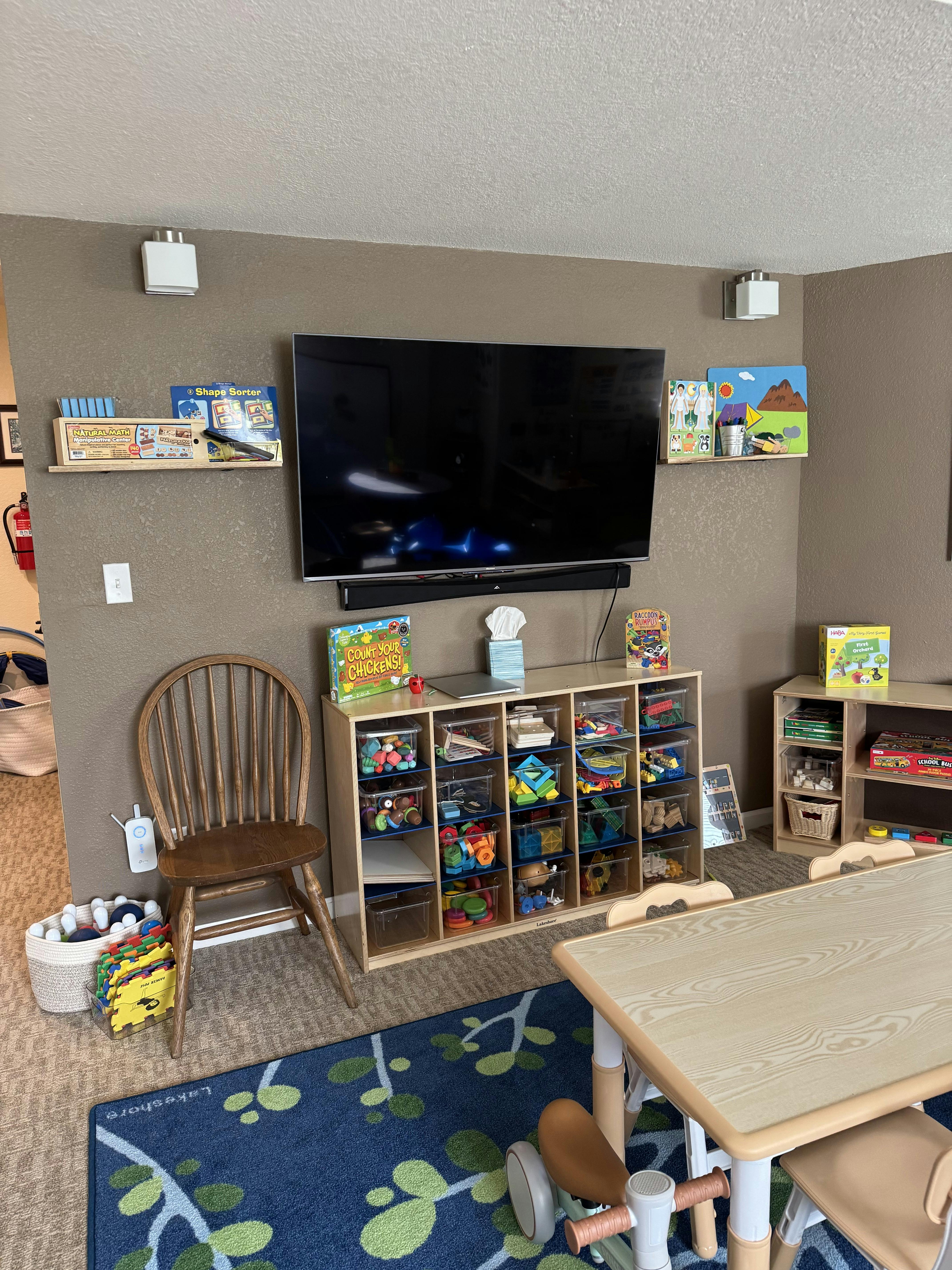 Classroom with a TV, toy storage, and small tables