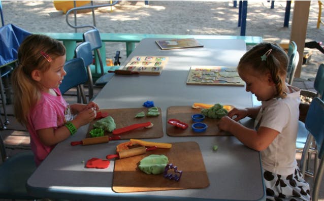 Two children playing with modeling clay at a table