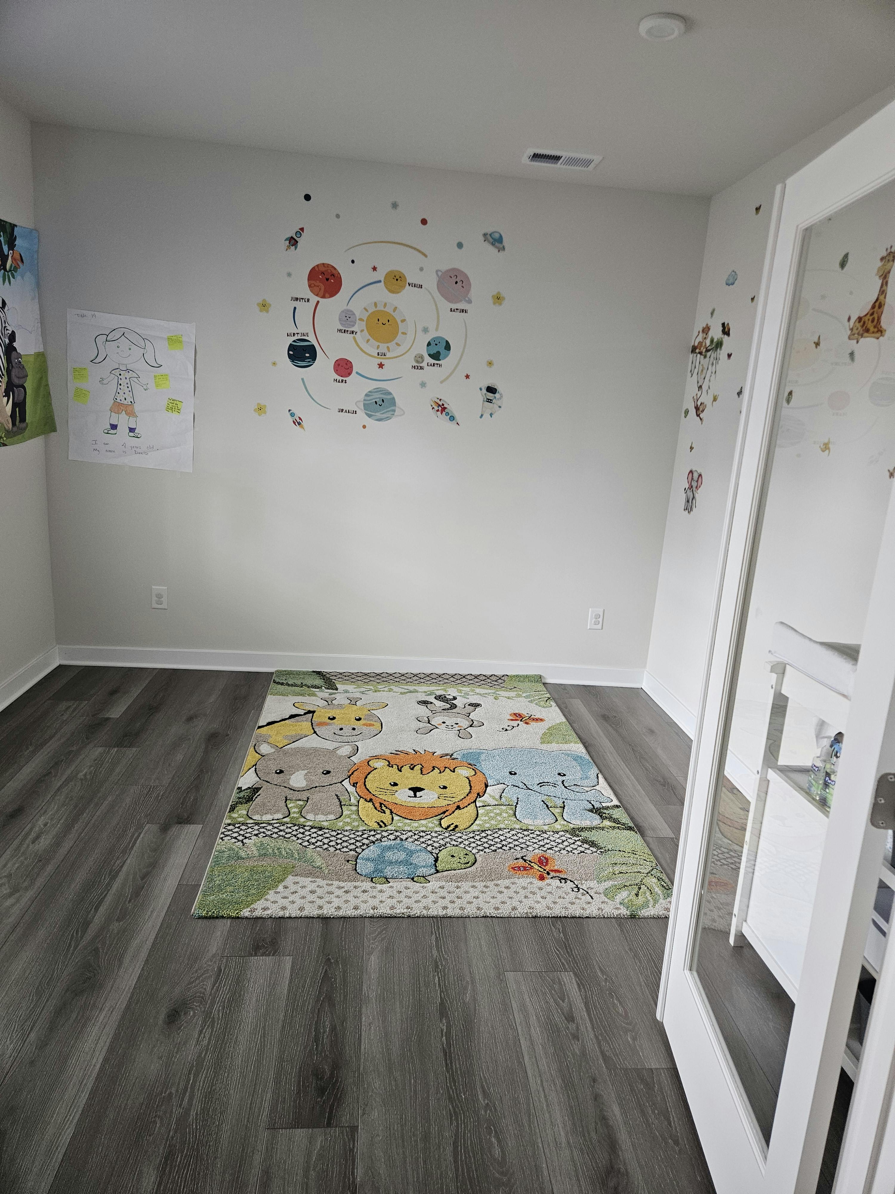 child's room with solar system wall decal and animal rug