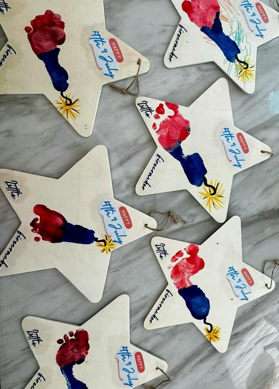 Star-shaped crafts with red and blue footprint art and "Happy 4th of July" text