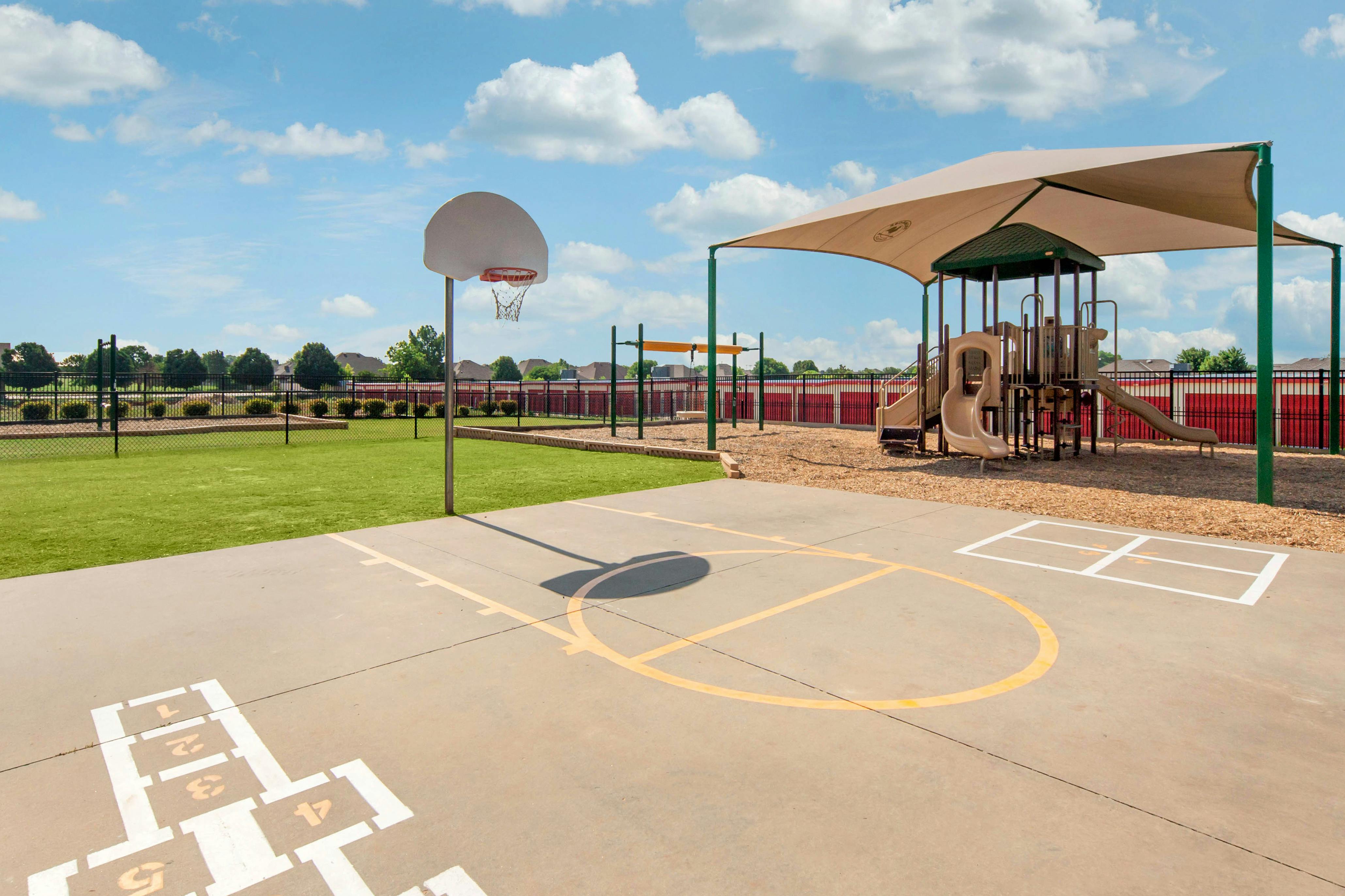 Basketball hoop, hopscotch, and shaded playground with slides