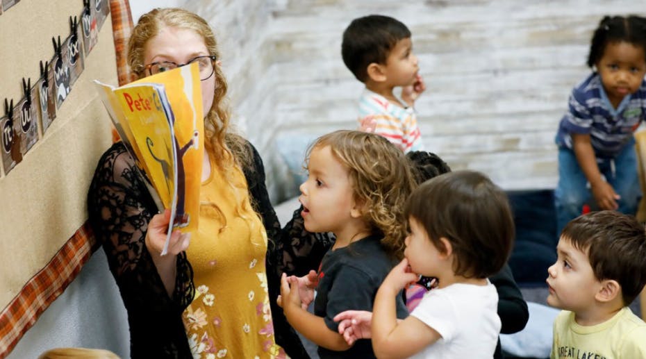 Person reading a book to a group of children