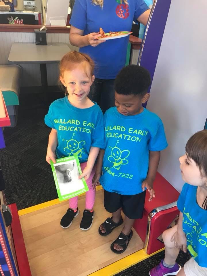 Two children in blue shirts holding a framed picture