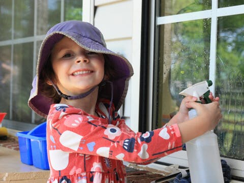 Child in a hat spraying a window