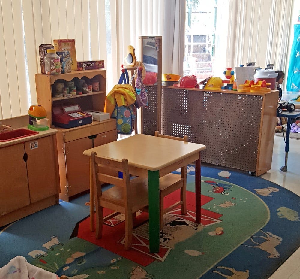 Child-sized table and chairs in a classroom with play furniture