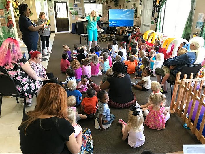 Adults and children sitting on the floor in a classroom