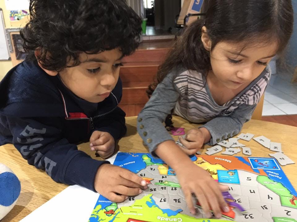 Two children playing with a map puzzle