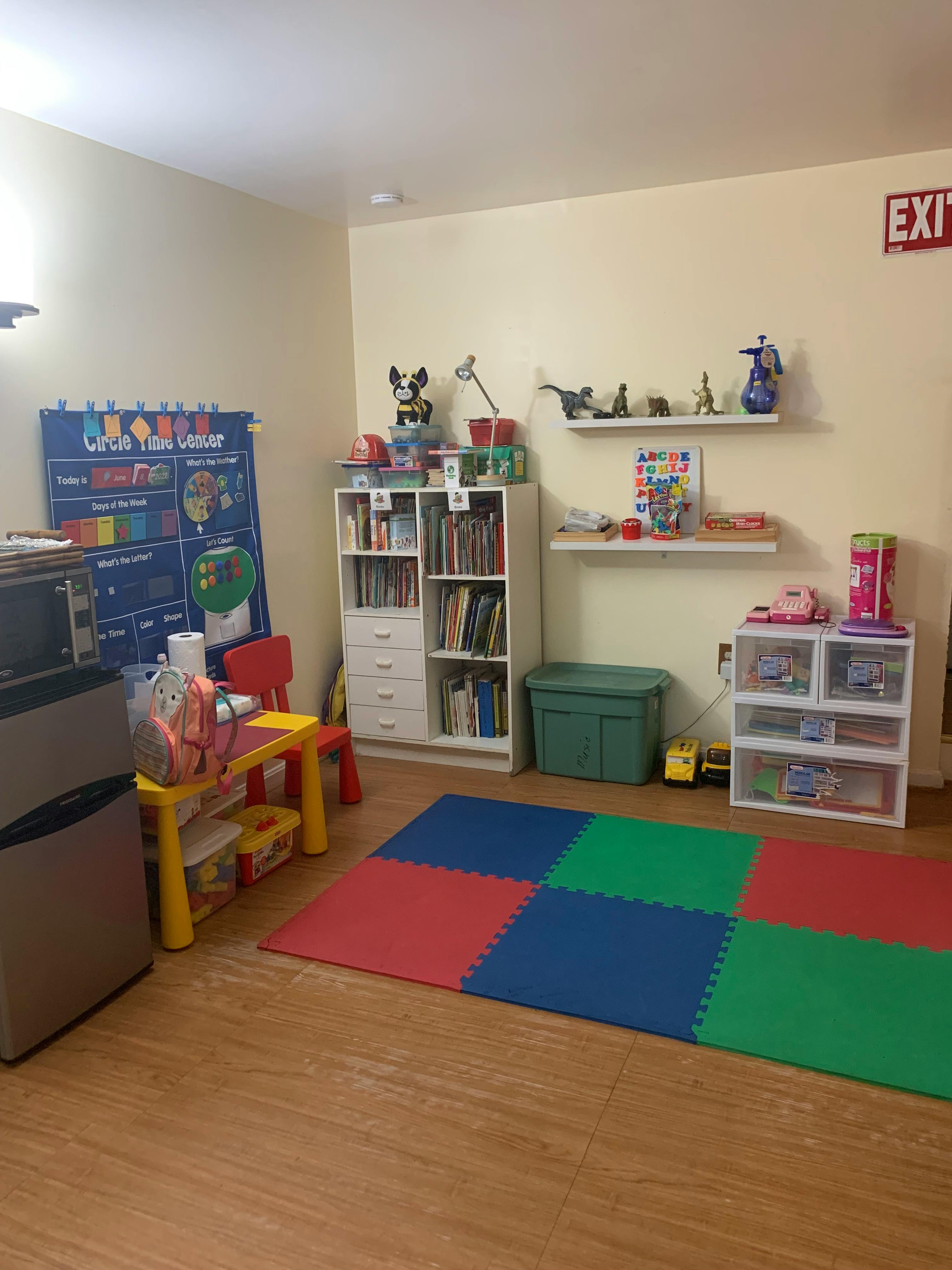 Playroom with colorful floor mats, small table and chairs, and shelves with shelves of shelves