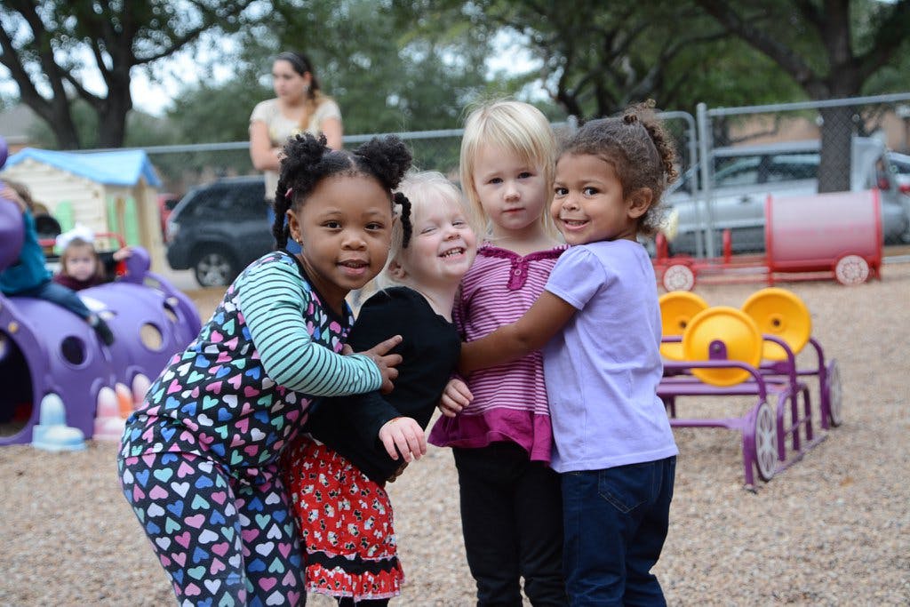 Four children hugging on a playground