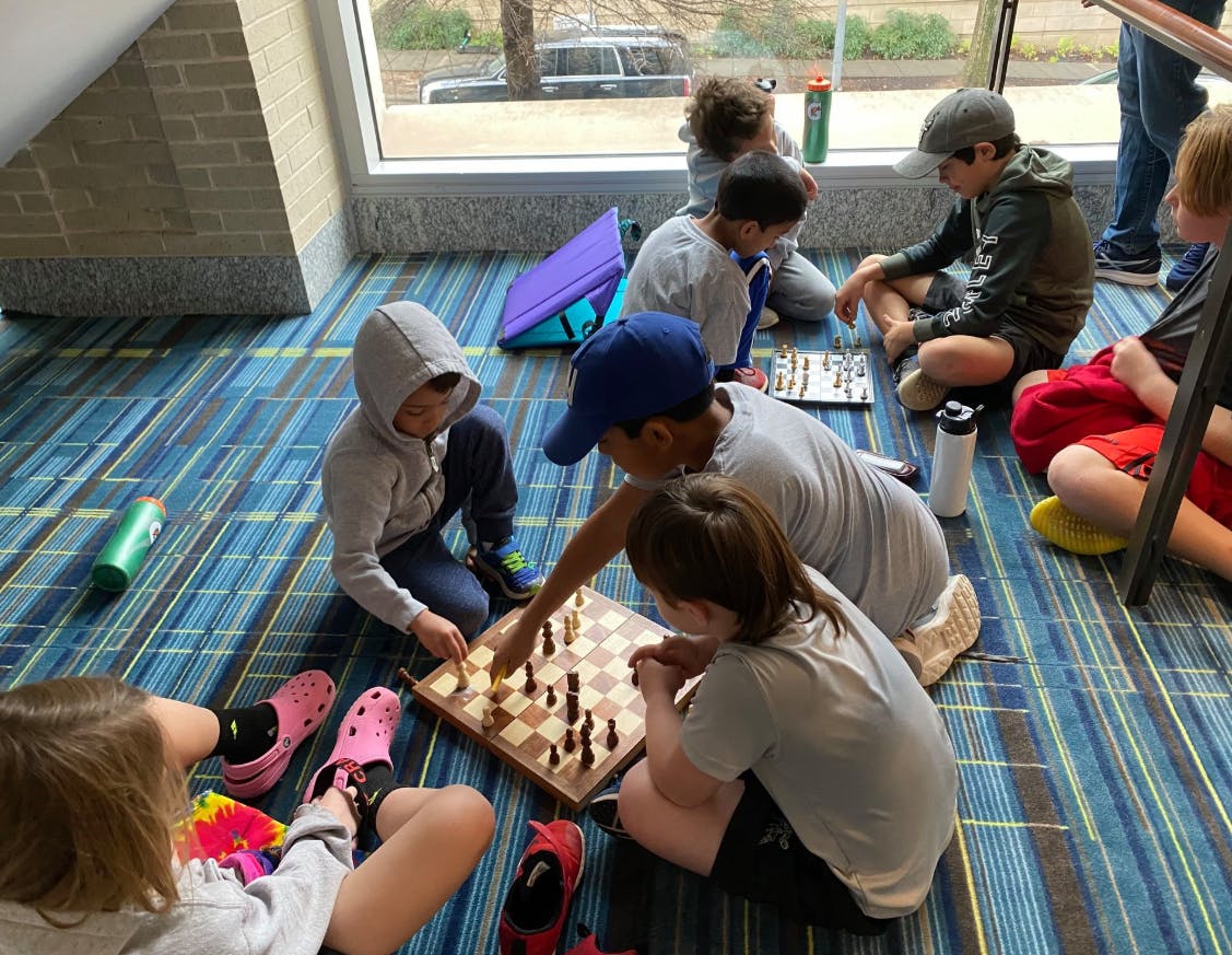 Children and adults playing chess on the floor