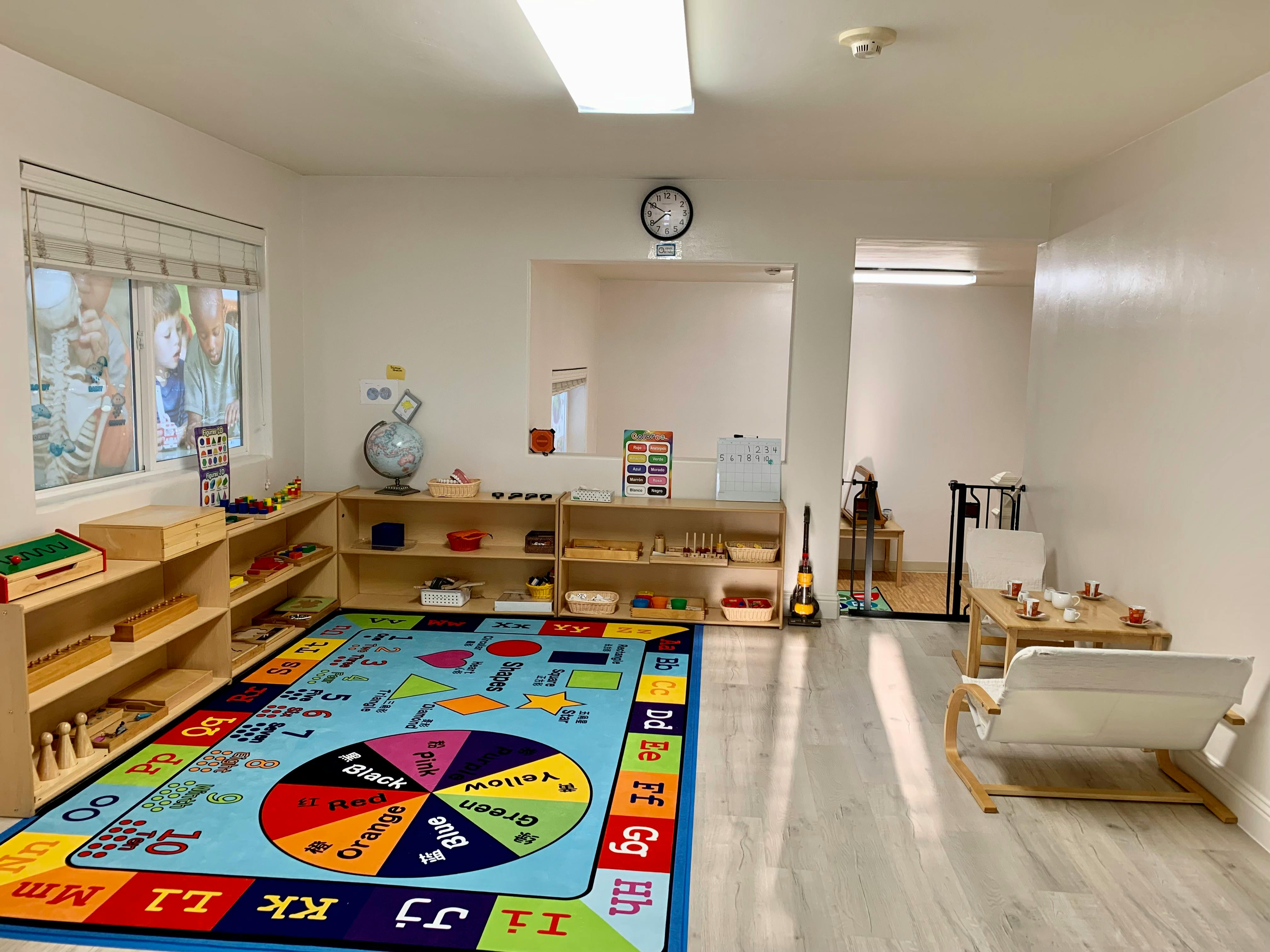 Classroom with a colorful rug, wooden shelves, and tables