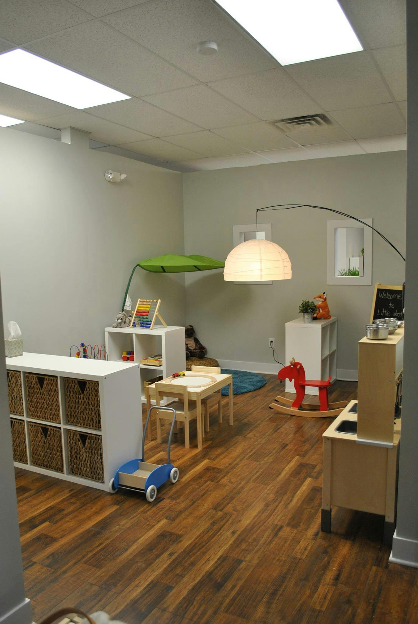 Playroom with small tables, storage units, and a red rocking horse