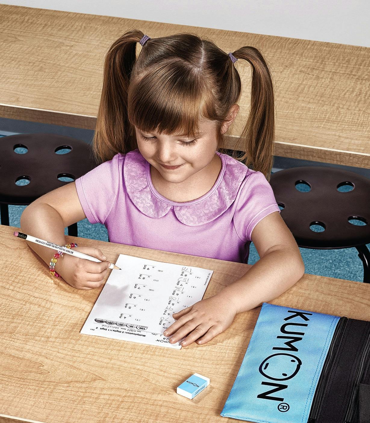 Child writing on a math worksheet at a desk