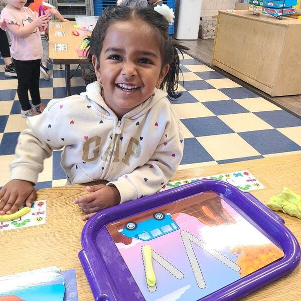 Child at a table with a drawing toy