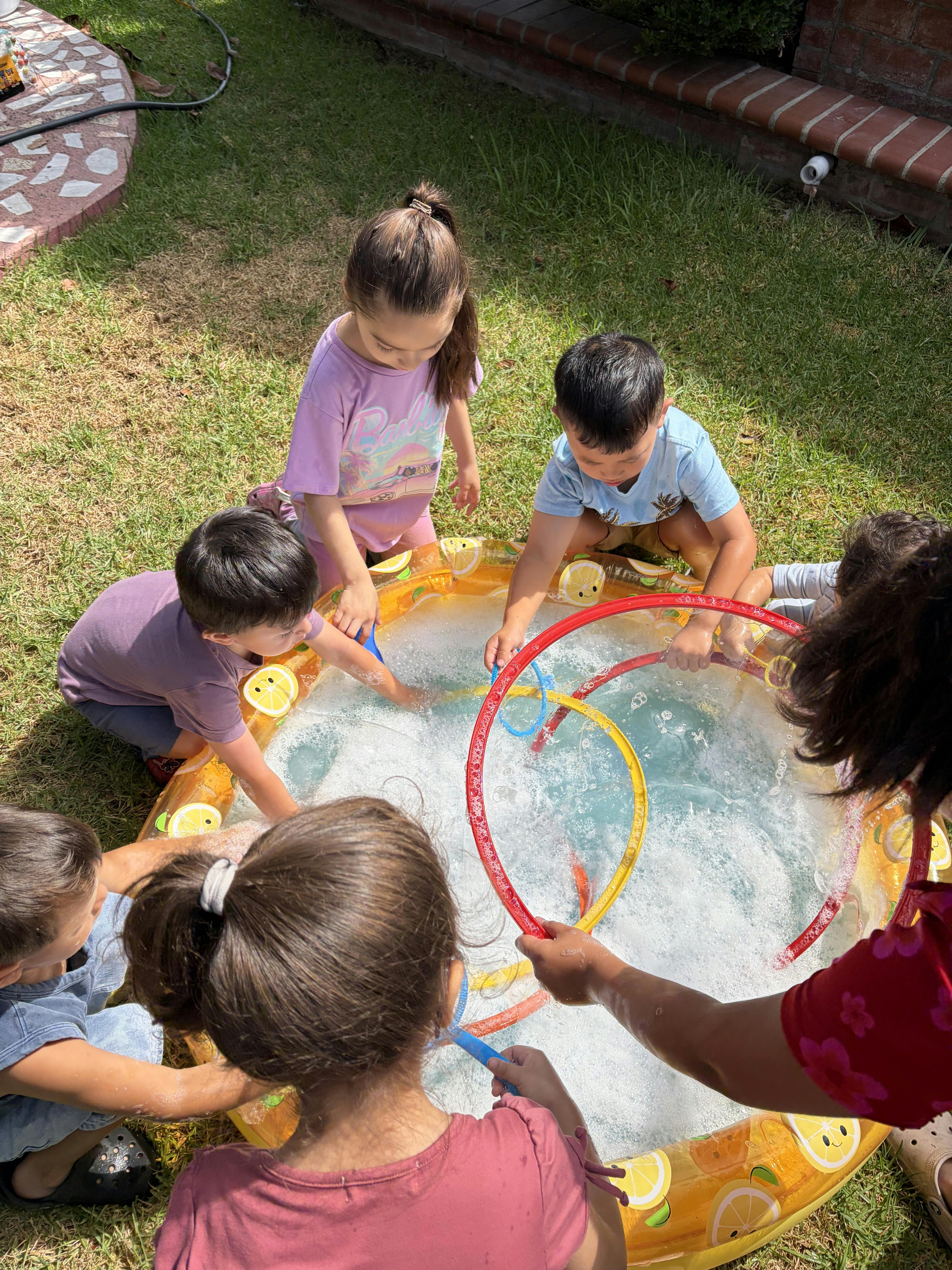 Group of children playing with bubble wands in a small inflatable pool