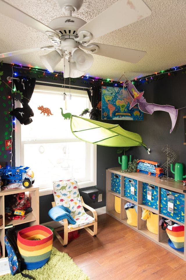 Child's room with dinosaur decor, a ceiling fan, and storage shelves