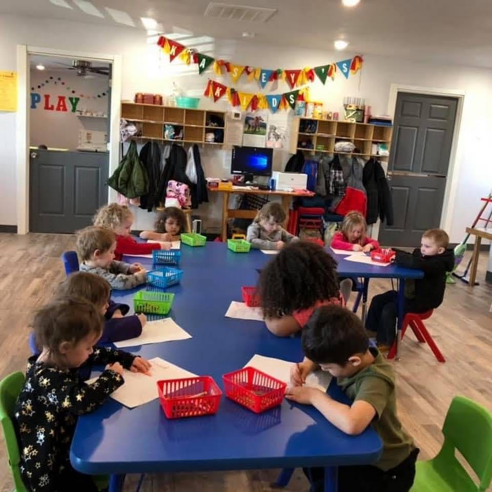 Children sitting at tables in a classroom, drawing and coloring