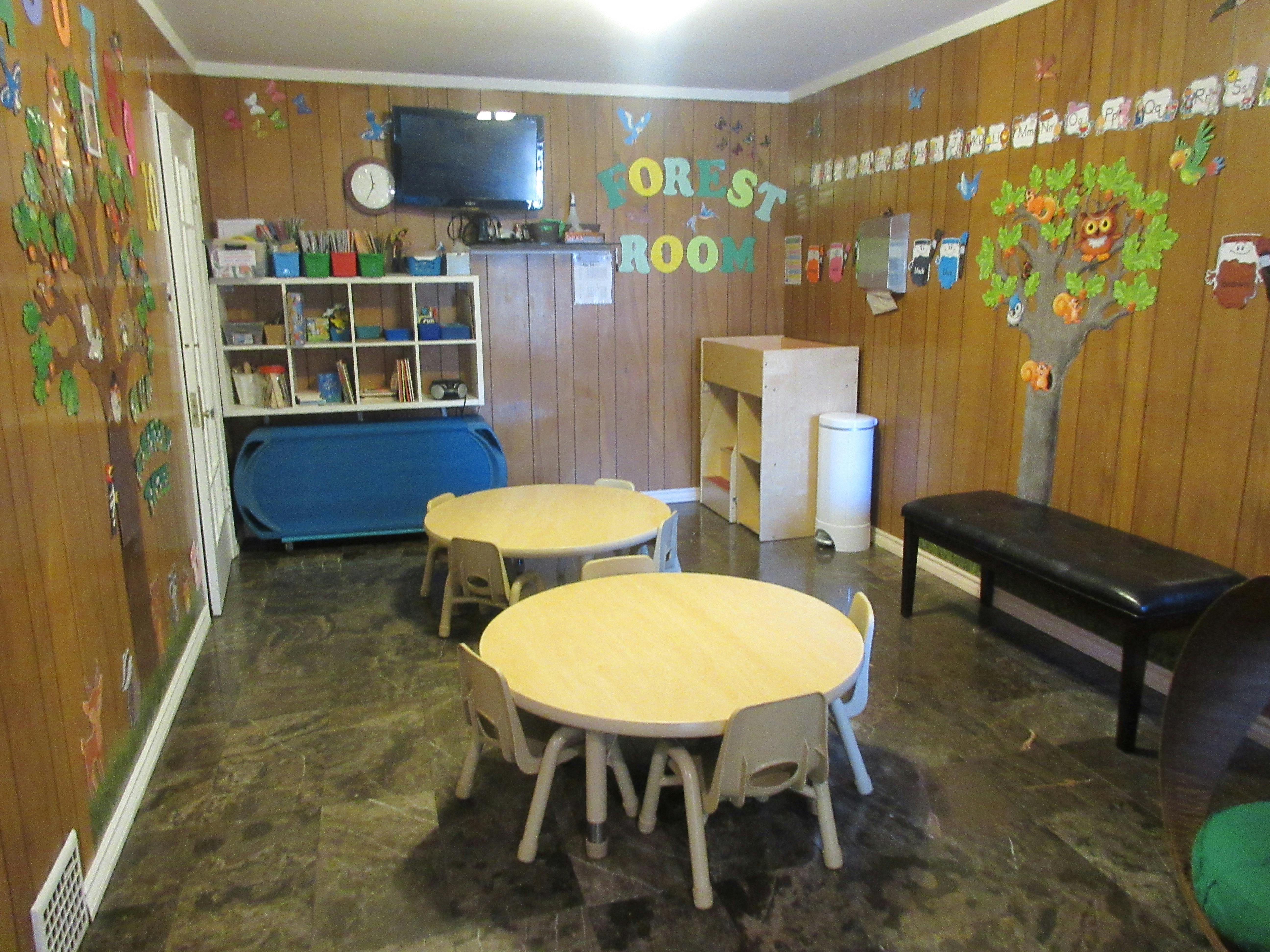 Classroom with small tables and chairs, shelves, and wall decorations