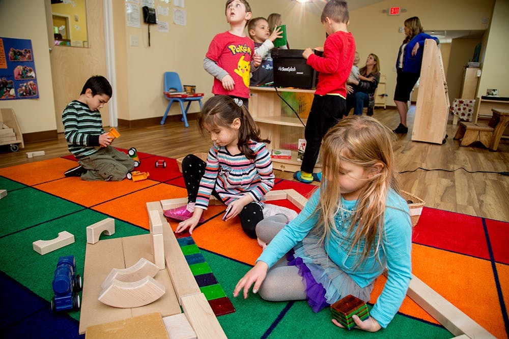 Children playing with blocks and toys on a colorful rug