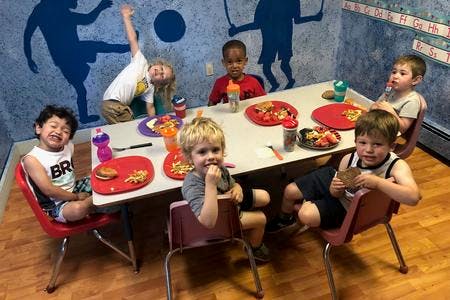 Children eating at a table in a classroom