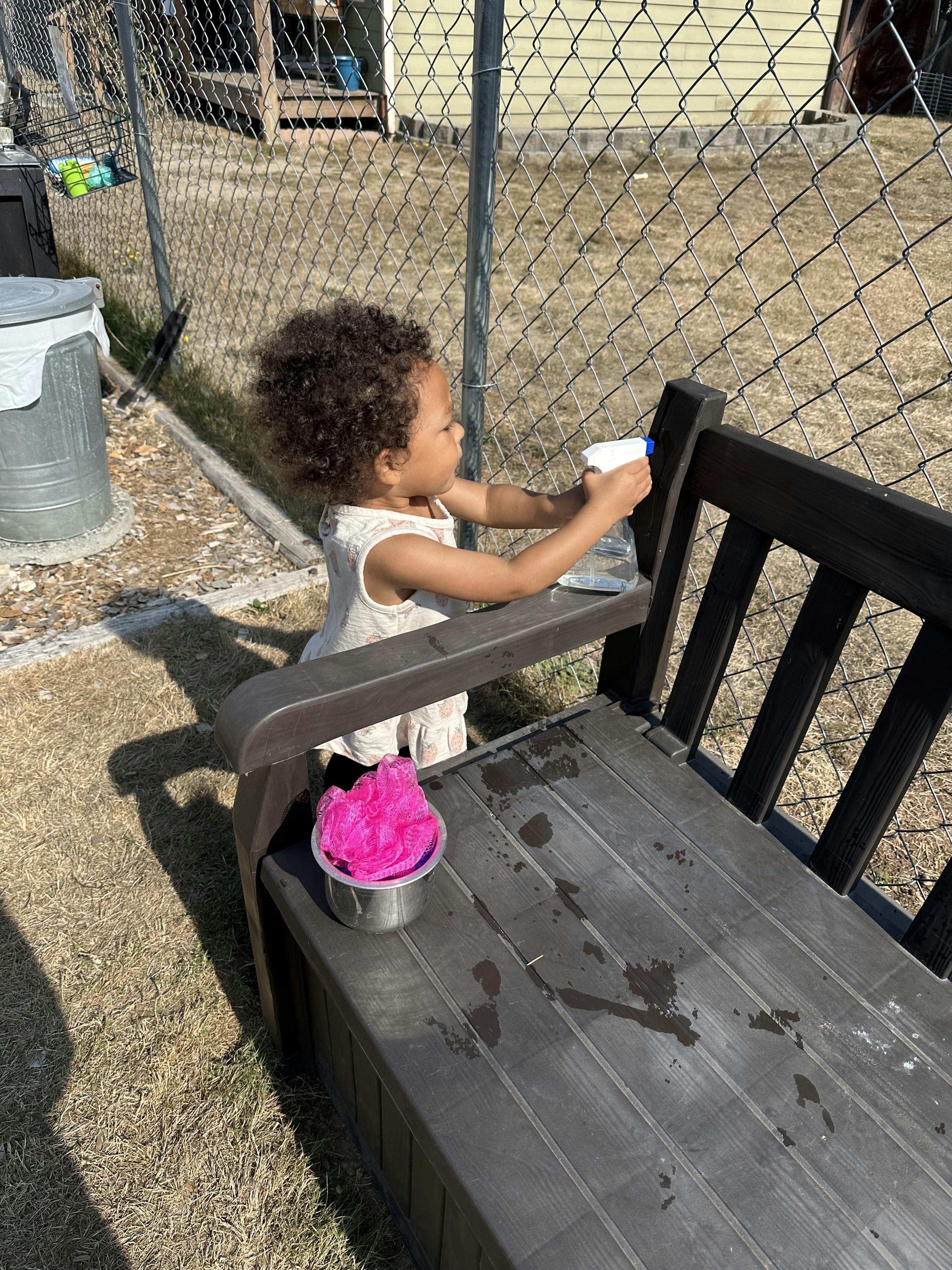 Child spraying water on a bench