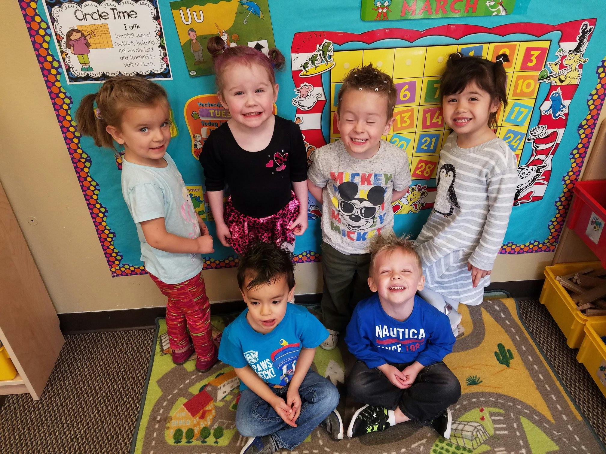 Six children posing for a photo in a classroom