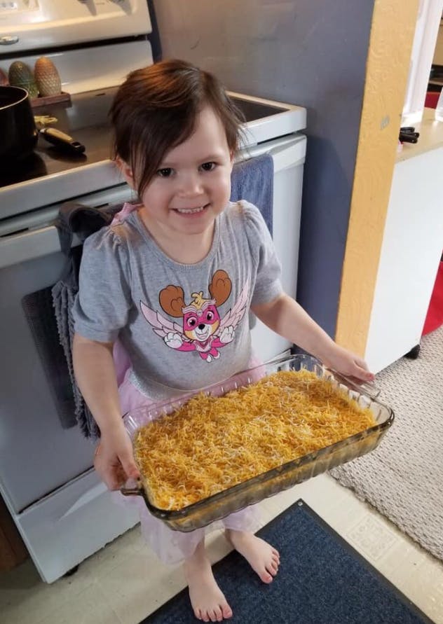 Child holding a baking dish with food