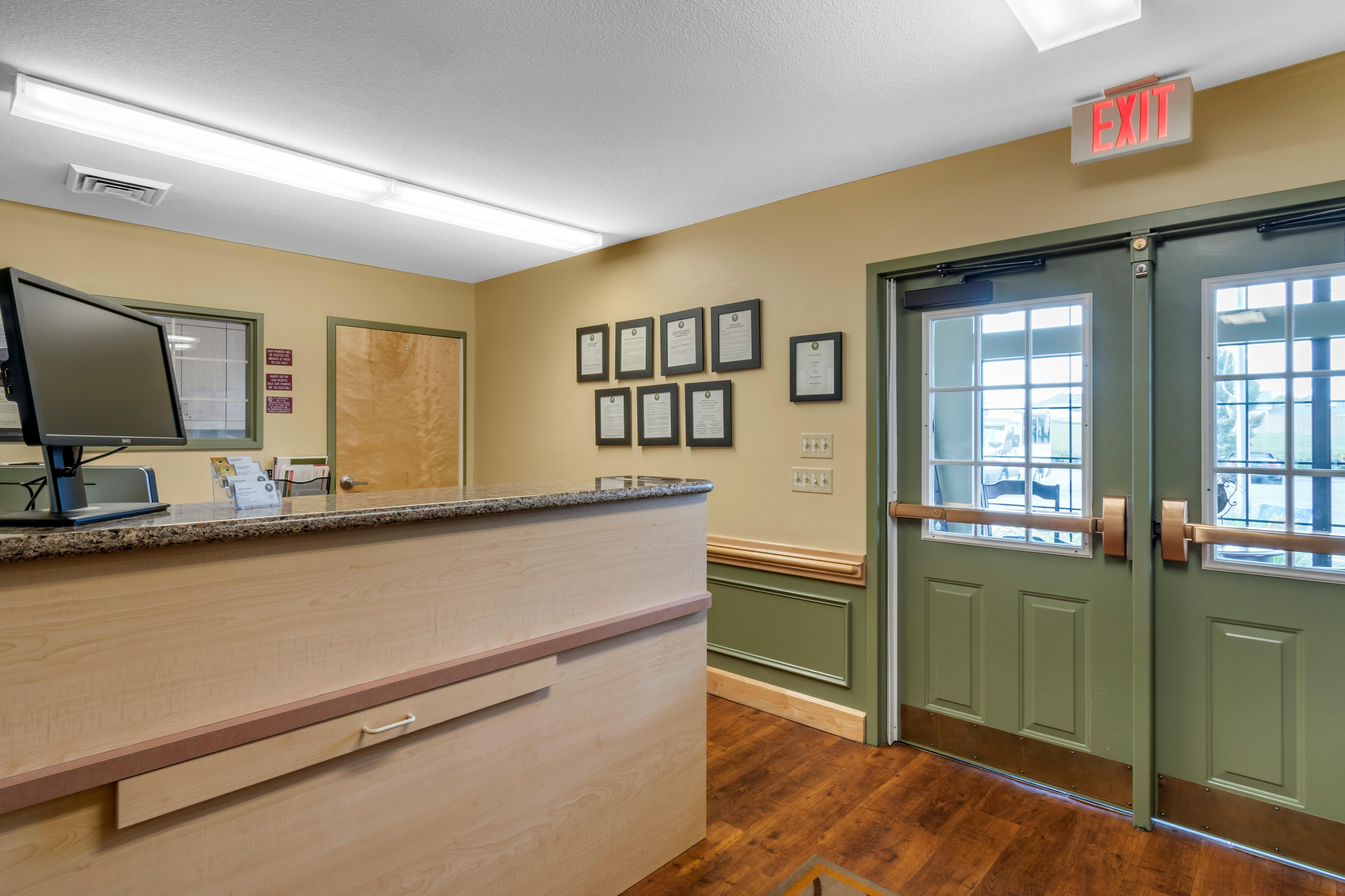 An empty reception desk with two green doors and an exit sign