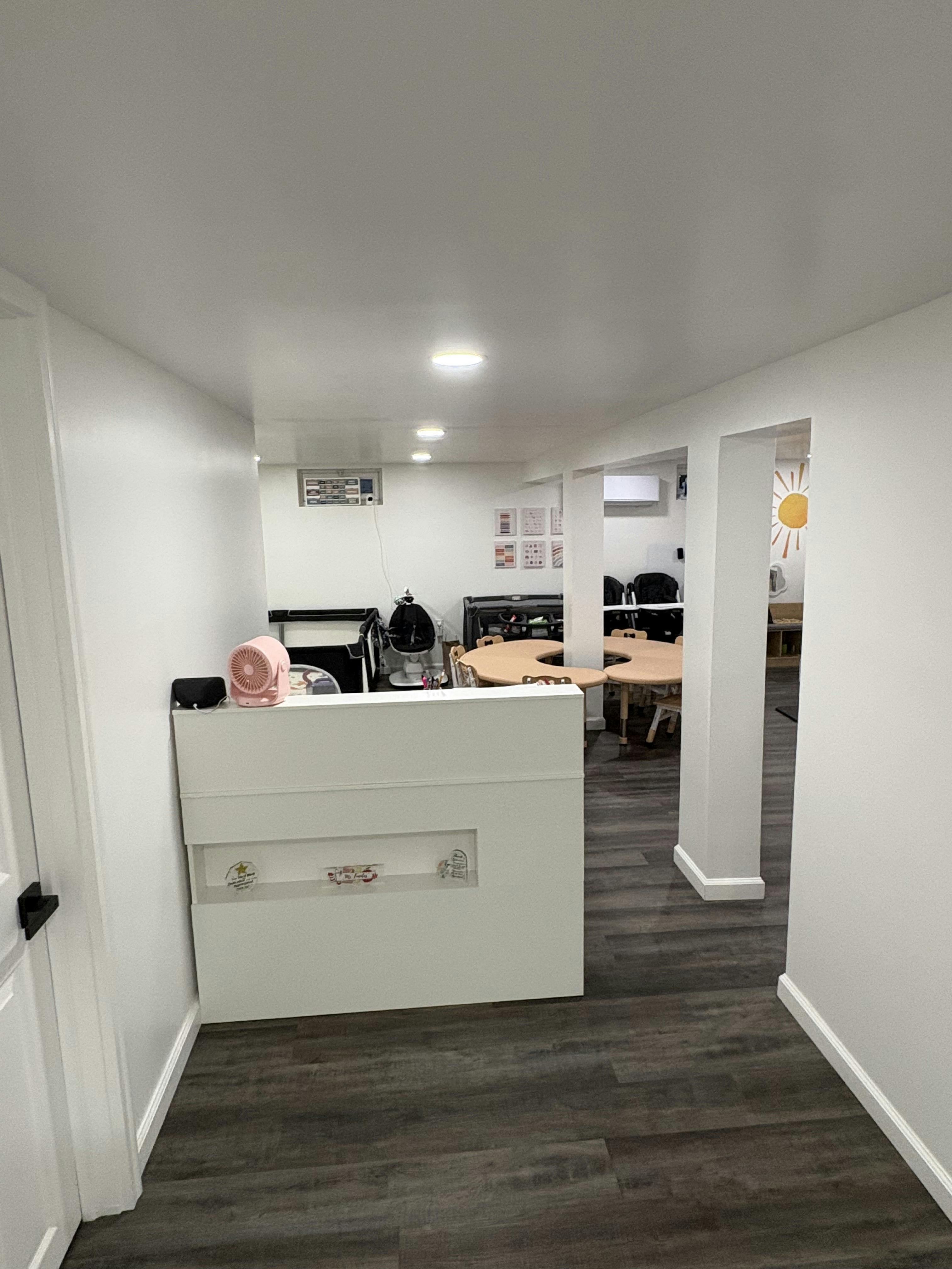 white reception desk with a pink fan in a room with play tables