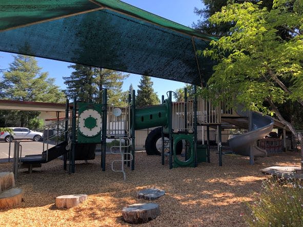 Playground with slides and climbing structures under a shade canopy