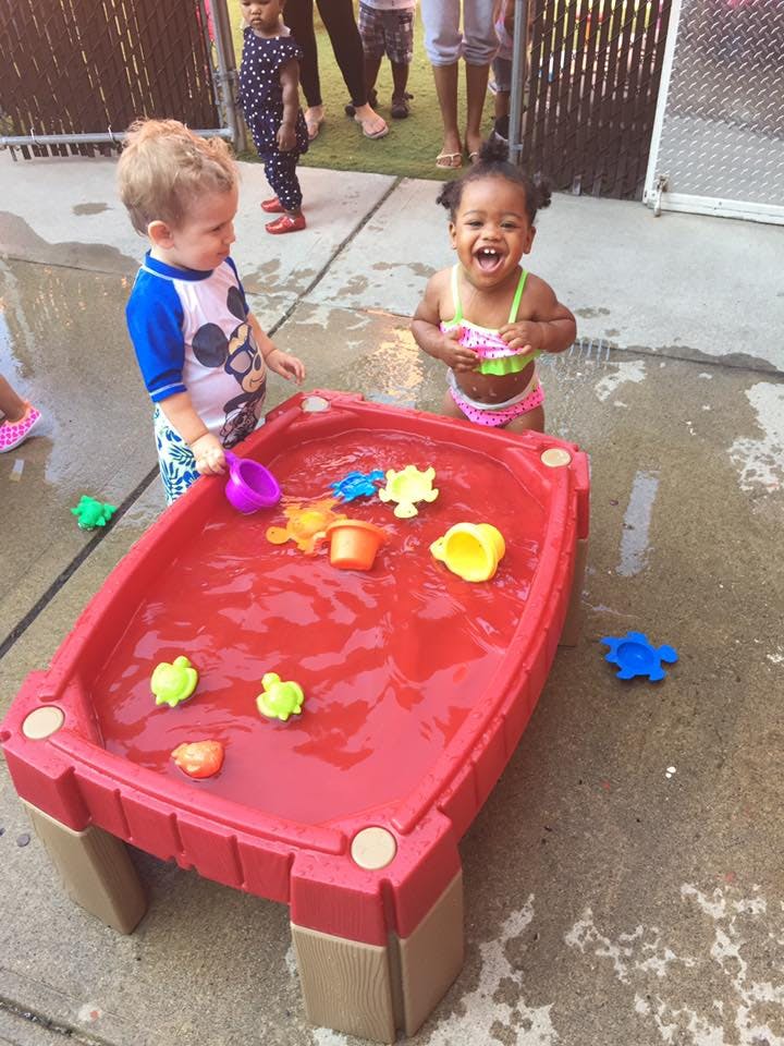 Two children playing with a red water table