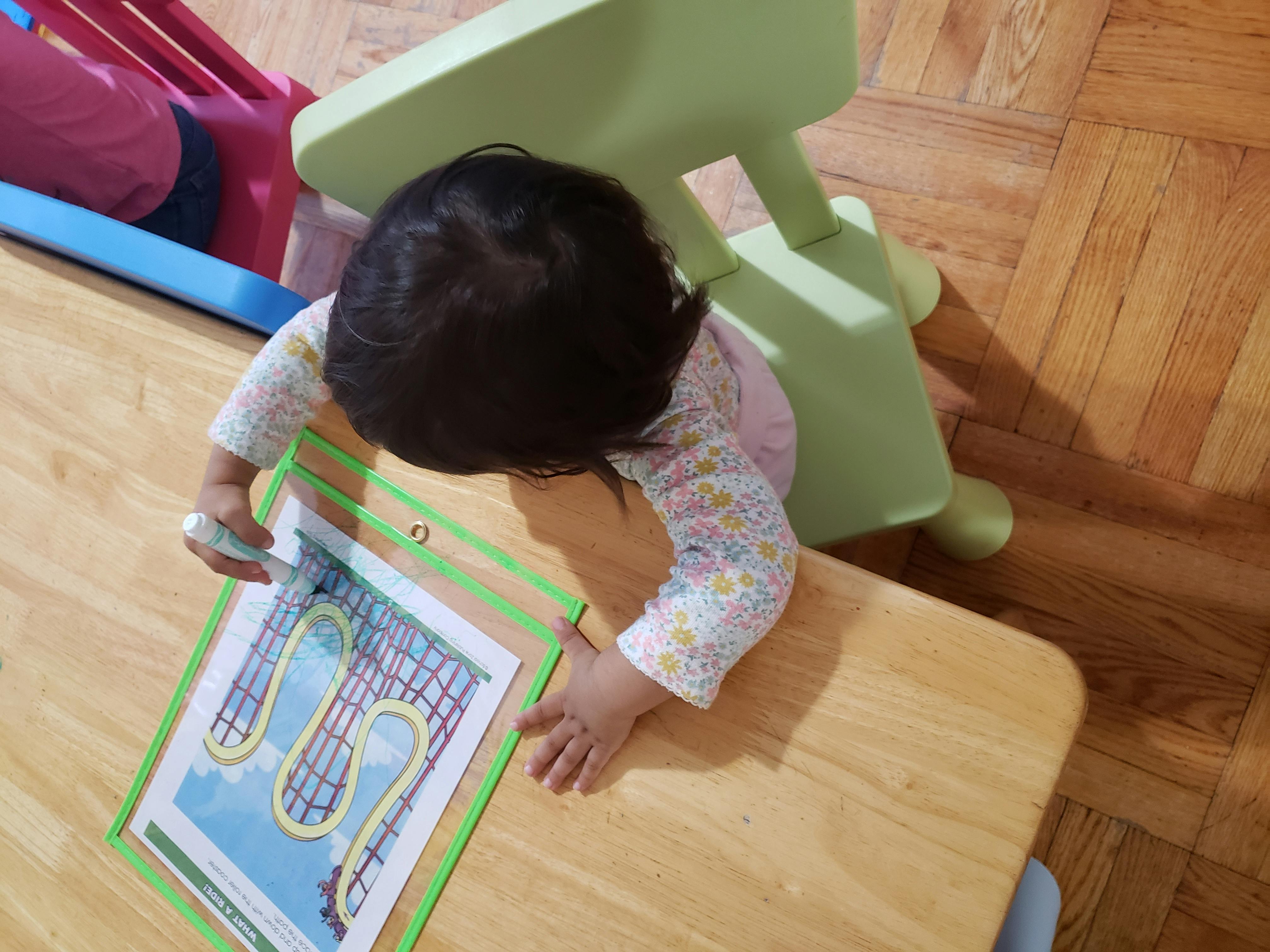 Child drawing on a paper with a marker at a table