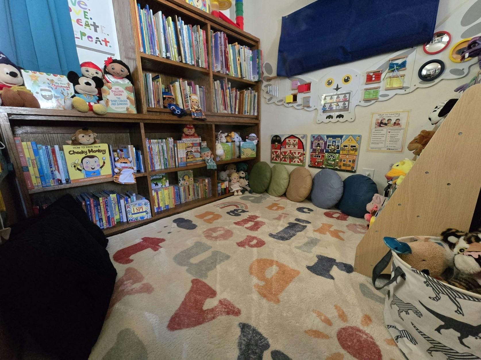 Children's reading nook with bookshelves, alphabet rug, and cushions
