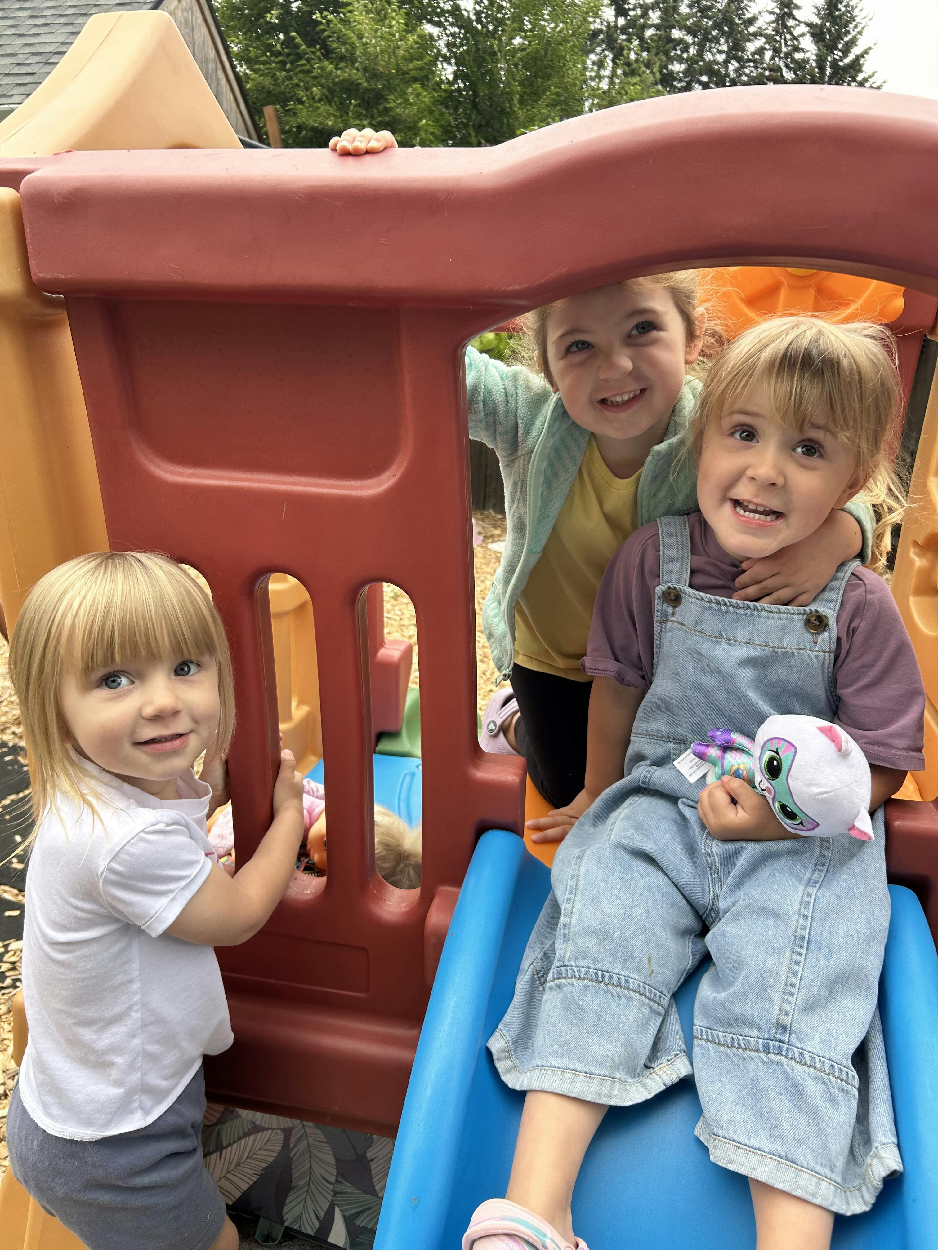 Three children playing on a plastic playground structure
