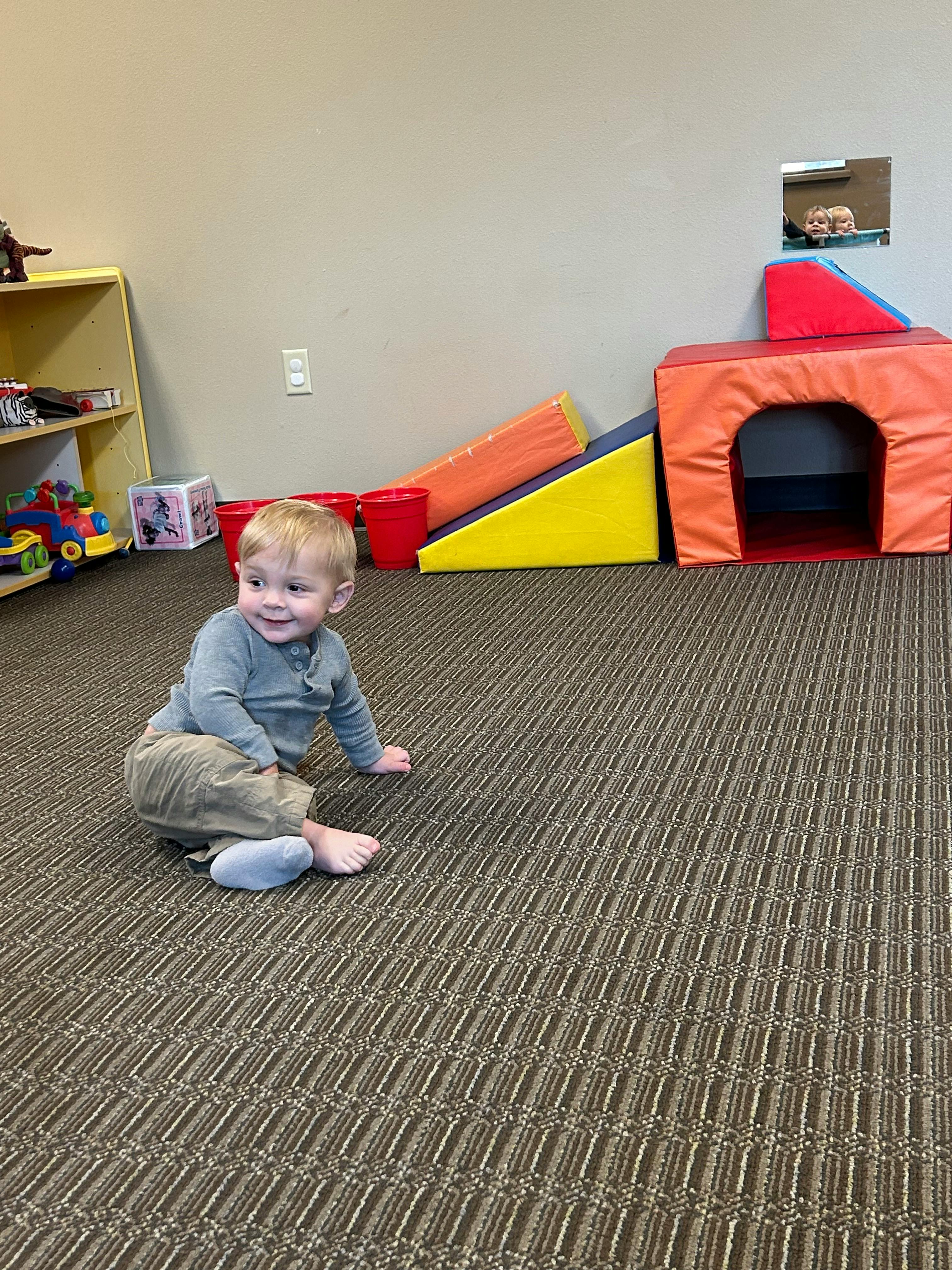 Child sitting on carpet in a play area