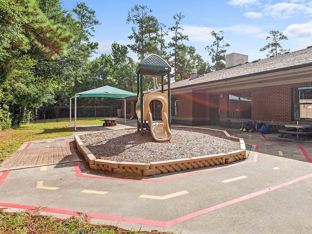Playground with a slide, canopy, and painted road on concrete
