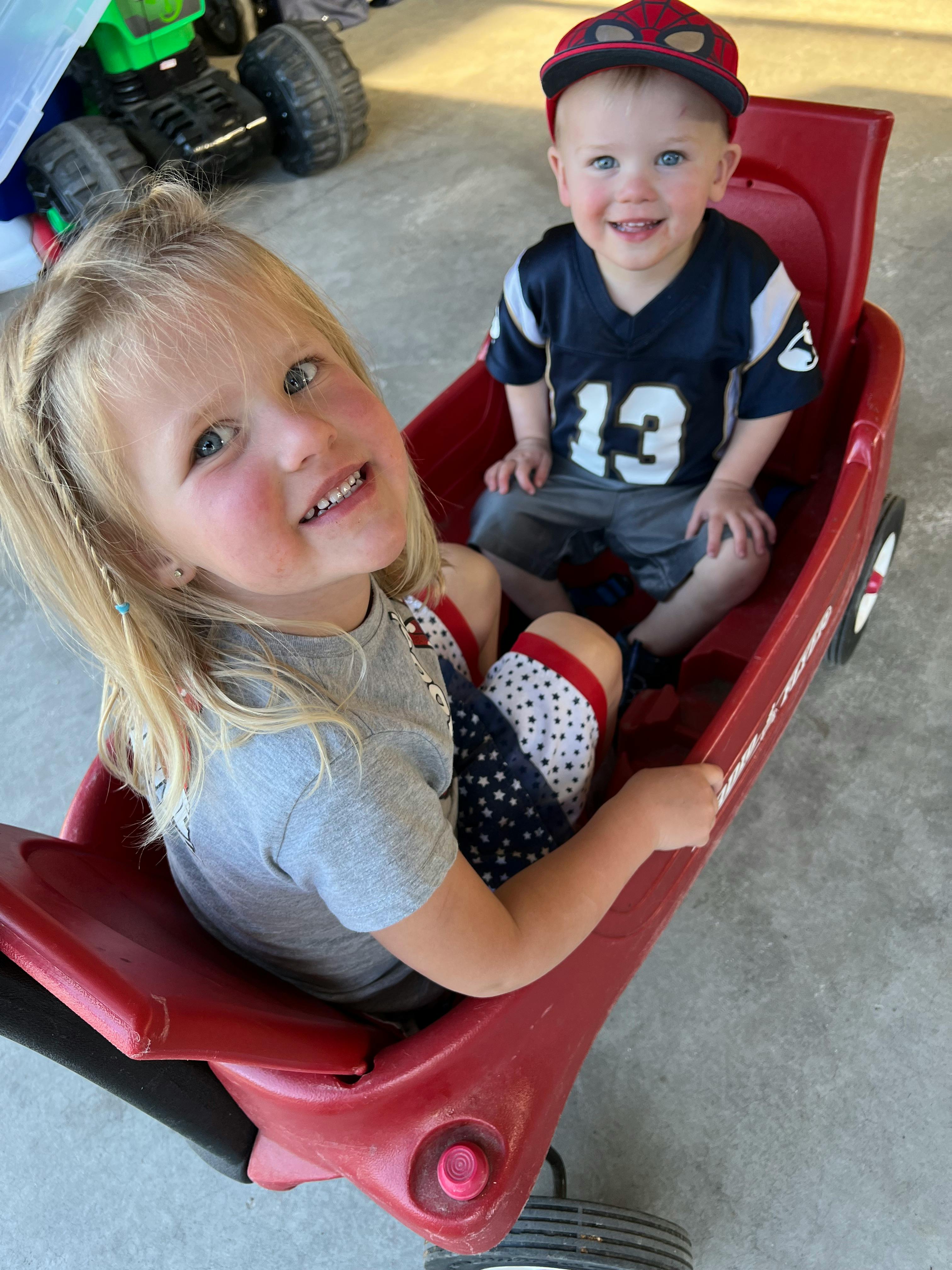 Two children sitting in a red wagon