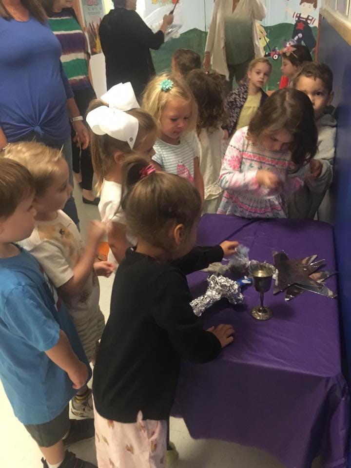 Children gathered around a table with objects on it