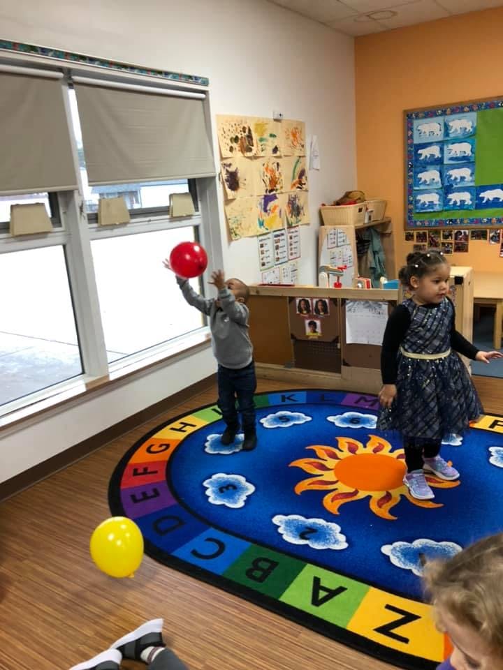 Child playing with a red ball in a classroom