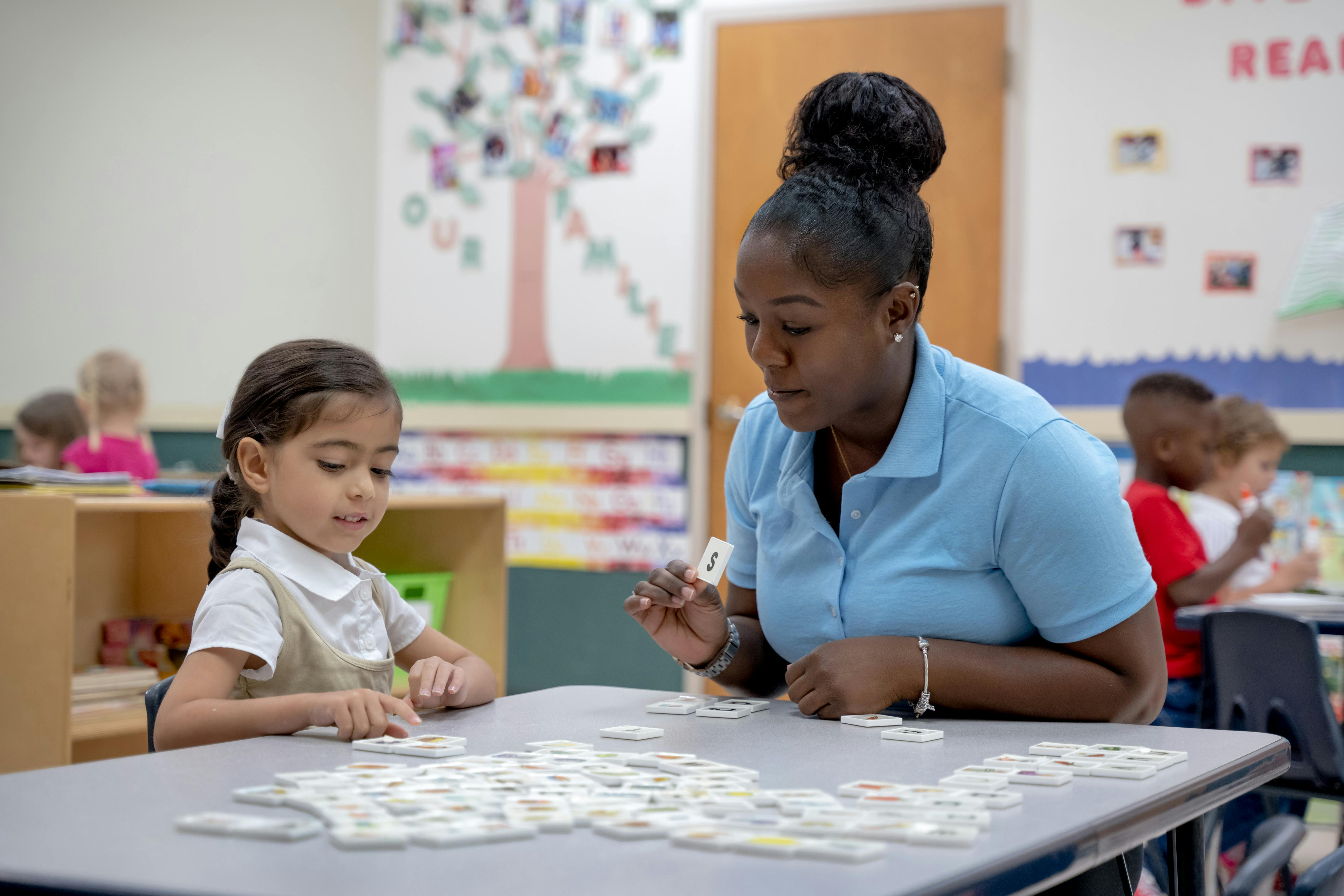 Adult and child playing a game with tiles at a table in a classroom