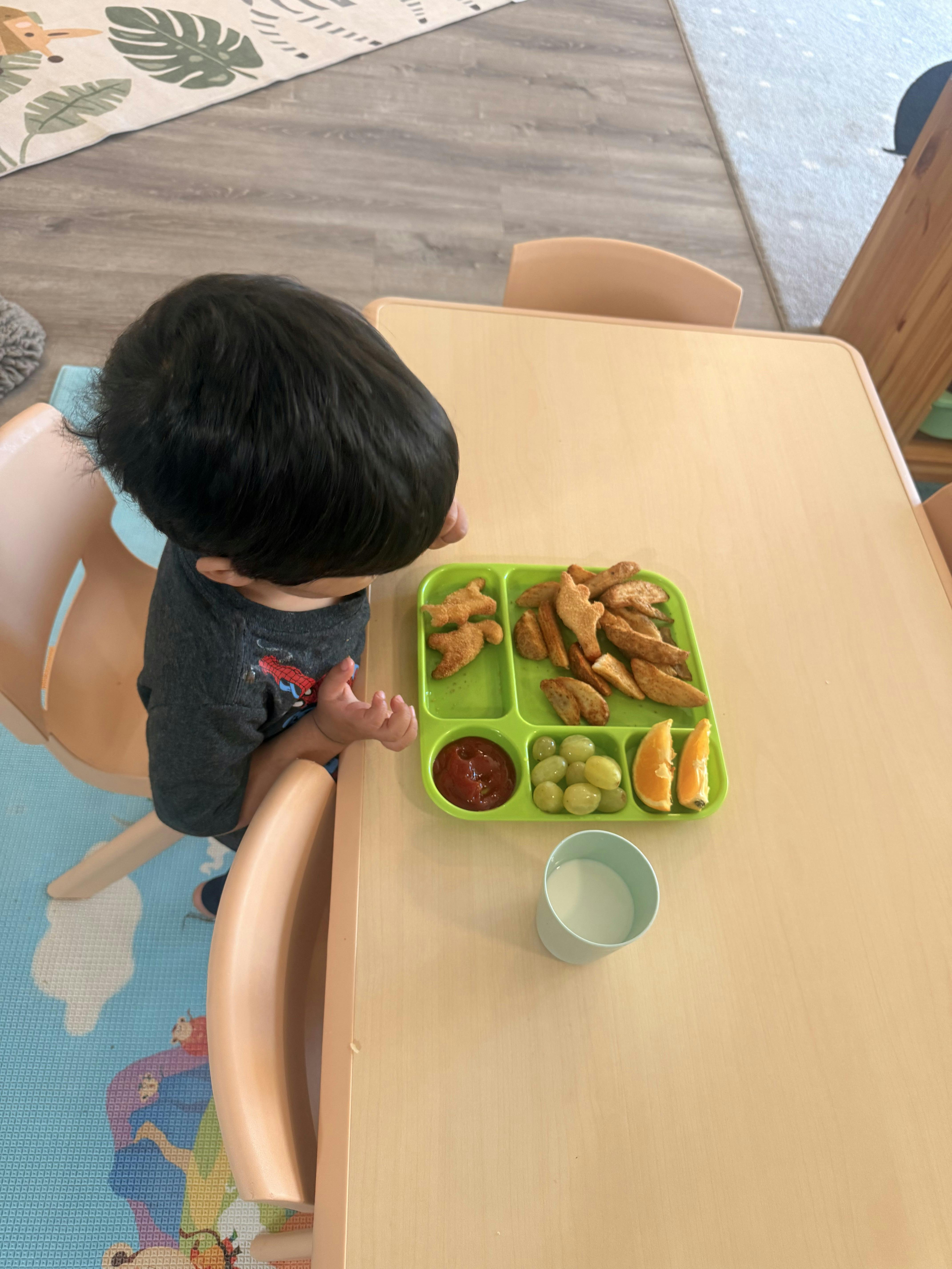 Child sitting at a table with a tray of food