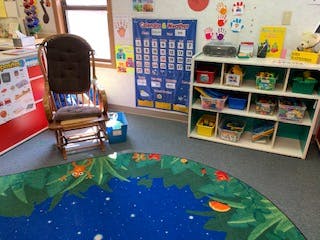 Classroom with a rocking chair, calendar, and storage shelves